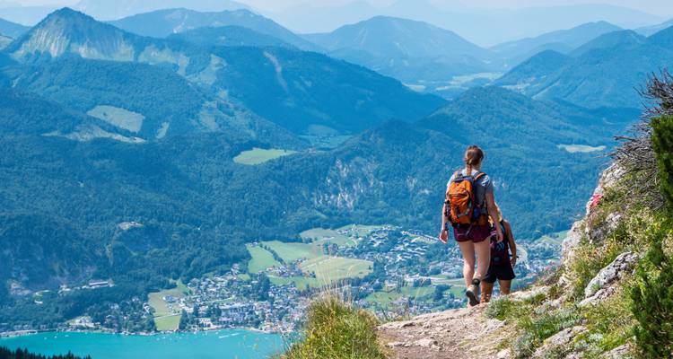 Une personne en randonnée avec une vue panoramique sur une vallée et des montagnes.