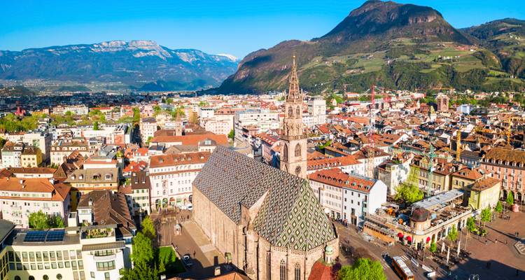 Ein großer Stadtplatz mit einer imposanten Kathedrale und einer bergigen Kulisse.