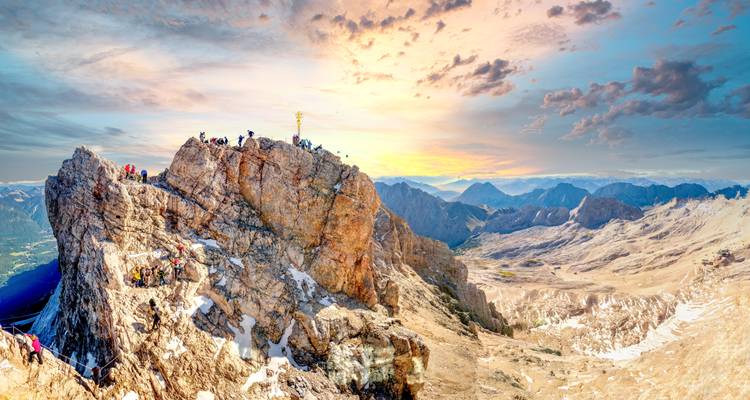 Ein dramatischer Berggipfel mit Kletterern bei Sonnenuntergang.