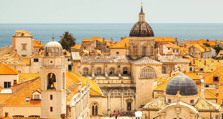 Ville historique avec une architecture à coupoles surplombant la mer.