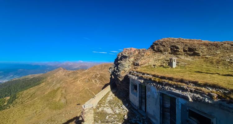 Zerklüfteter Bergkamm mit Ruinen einer alten Steinbefestigung unter tiefblauem Himmel.