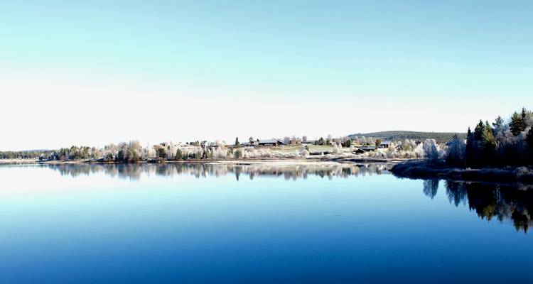 A bright landscape with a lake and distant buildings.