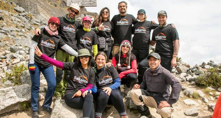 Groupe de personnes posant avec des t-shirts assortis sur un sentier rocheux.