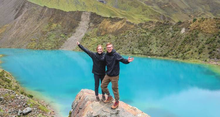 Couple posant près d'un lac bleu vibrant dans une région montagneuse.