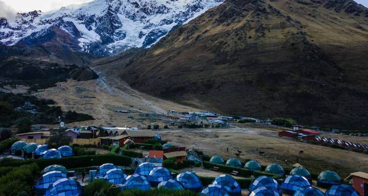 Paysage montagneux avec des tentes dômes transparentes.