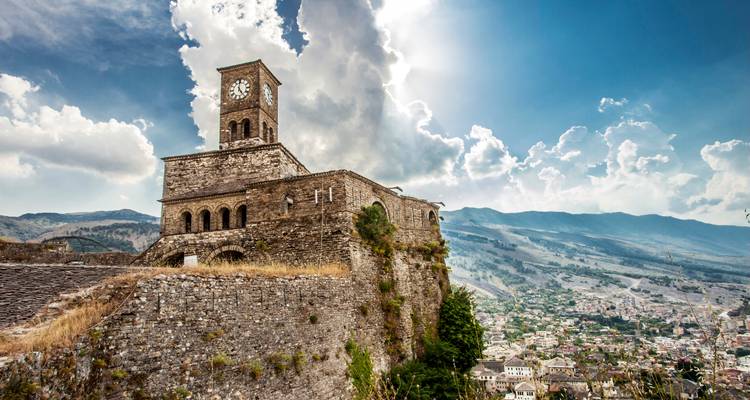Historische Festung mit Uhrenturm und Stadtblick im Hintergrund.