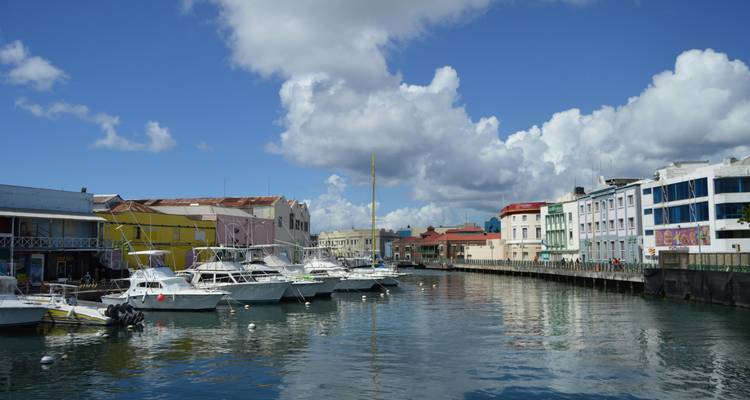 Marina avec plusieurs bateaux amarrés et des bâtiments colorés le long du front de mer.