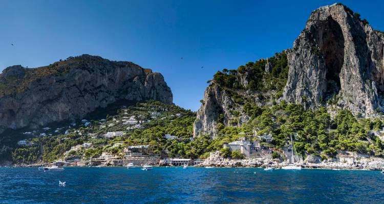 Espectaculares acantilados de piedra caliza y verdes laderas de Capri se alzan sobre las profundas aguas azules del Mediterráneo.