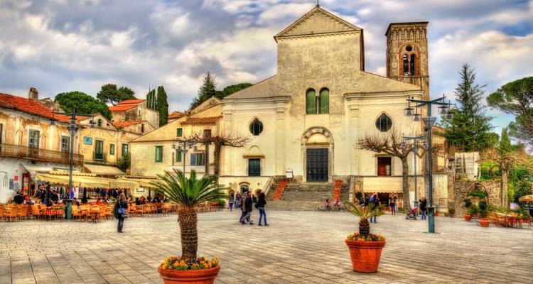 Encantadora plaza italiana con una iglesia histórica, cafés al aire libre y visitantes paseando.