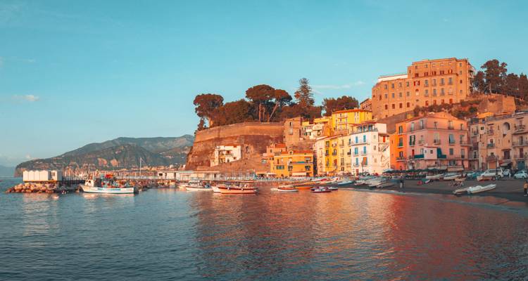 Panorama de la hora dorada de los coloridos edificios del puerto de Sorrento reflejados en aguas tranquilas.