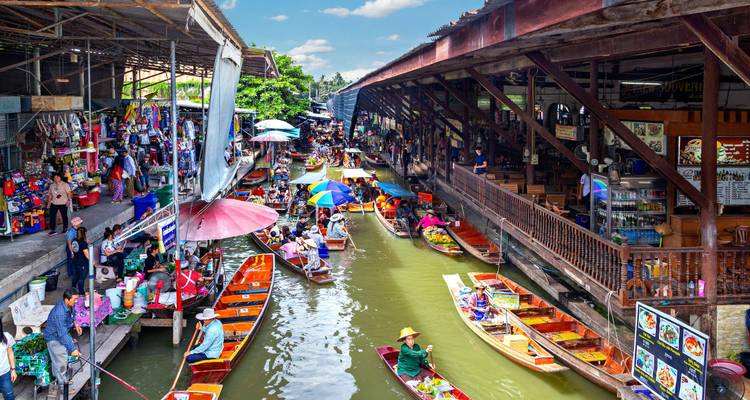 Mercado flotante vibrante con botes vendiendo productos y sombrillas coloridas.
