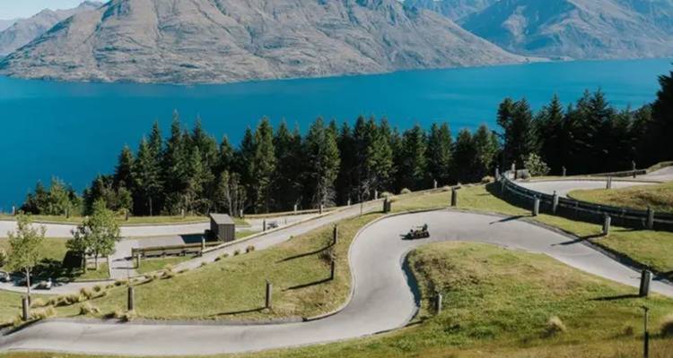 Vista panorámica de una carretera serpenteante con vista a un gran lago azul.