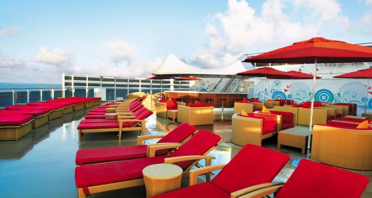 Cubierta solar en un crucero con tumbonas y mesas coloridas.
