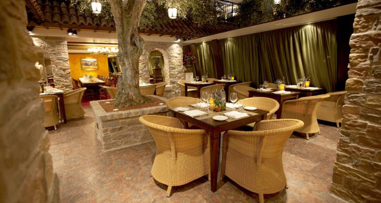 Interior acogedor de restaurante con iluminación cálida y sillas de mimbre alrededor de las mesas.