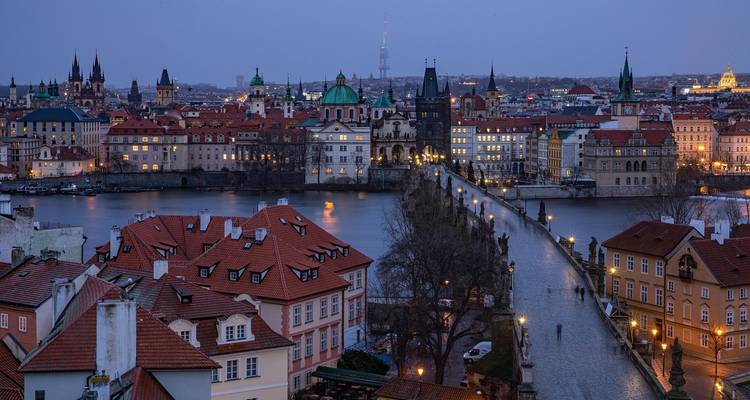 Historic Charles Bridge and Old Town with lights at dusk.