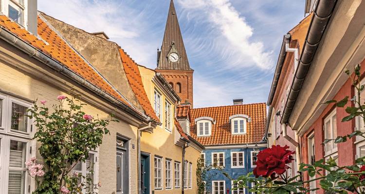 Charming street with colorful houses and a church tower in the background.