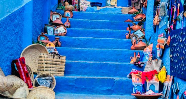 Blau gestrichene Stufen, die mit Töpferwaren und Kunsthandwerk in einer Marktumgebung geschmückt sind.