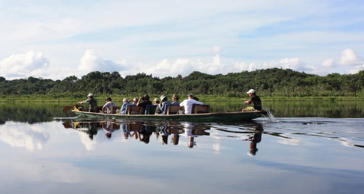 Een groep mensen die kanoën op een kalm meer omringd door bos.