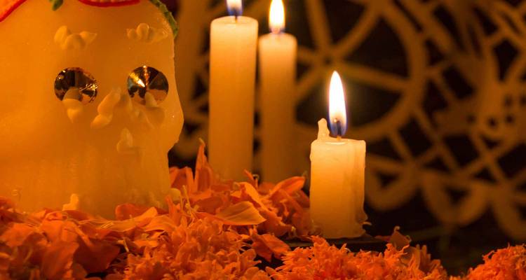 Kerzen und ein Zuckerschädel mit Ringelblumen.