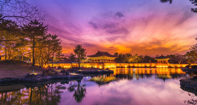 Verlicht traditioneel gebouw met reflectie in het water bij zonsondergang.