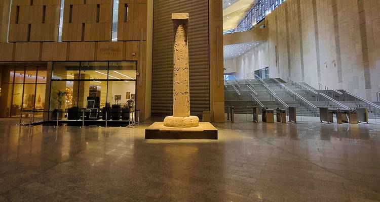 Intérieur d'un bâtiment moderne avec une colonne antique exposée au centre.