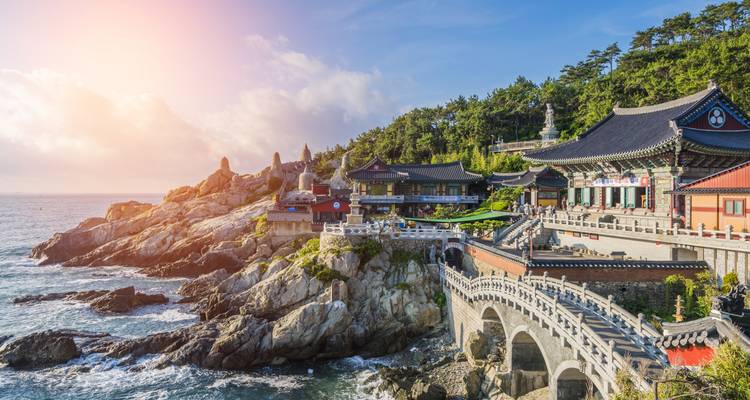 Un complexe de temples côtier avec un ciel lumineux et une vue sur la mer.