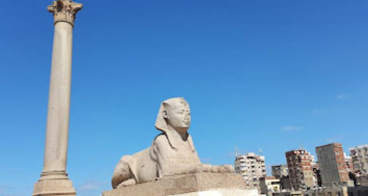 Sfinxbeeld met een zuil in een stedelijke omgeving.