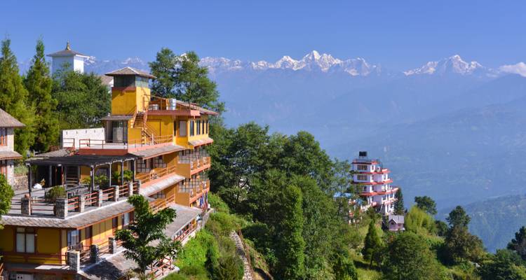 Hillside buildings with mountain views and clear skies.