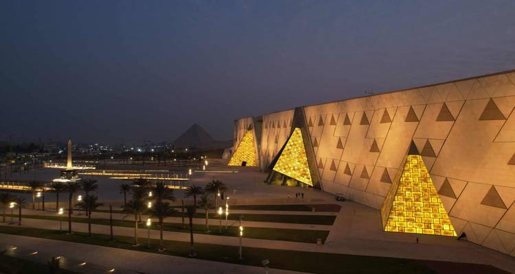 Structure moderne illuminée avec des pyramides au loin.