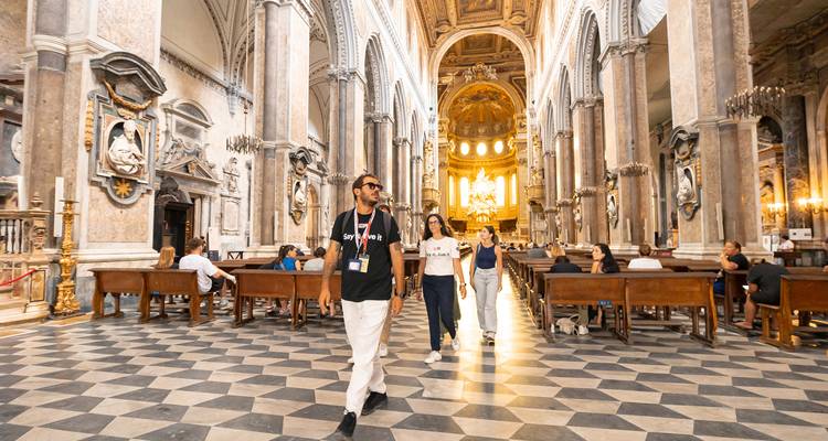 Interior of a grand church with people walking through.