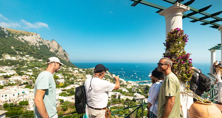 Tourists taking photos from a viewpoint overlooking the sea.