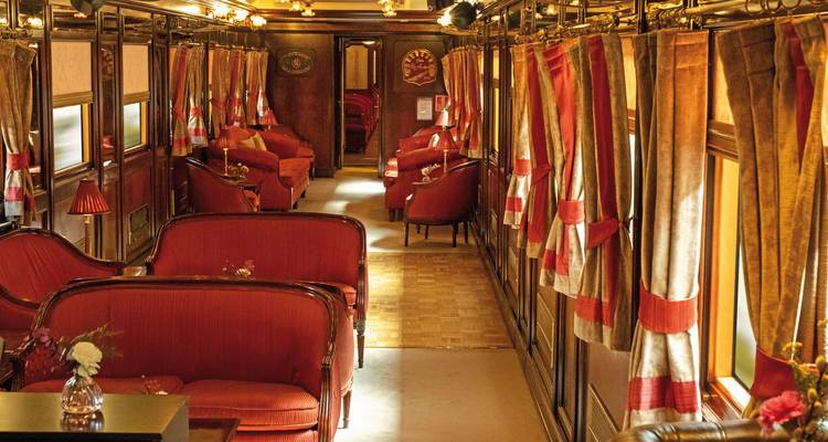 Intérieur luxueux d'un train vintage avec des sièges rouges.