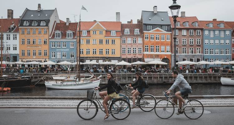 Cyclists riding by colorful townhouses along a canal.
