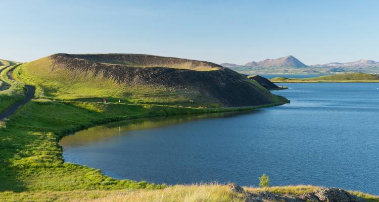 Cratère volcanique et lac avec un arrière-plan montagneux.