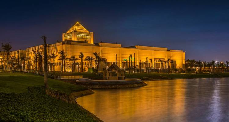A well-lit modern building by a water body at night.