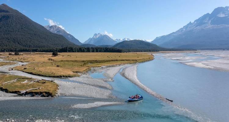 Vue panoramique d'une rivière avec un bateau et des montagnes en arrière-plan.