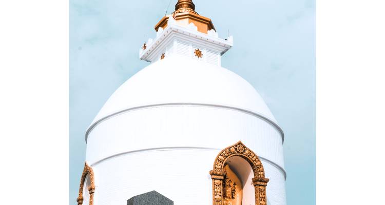 Close-up of a white stupa with intricate details under a clear sky.