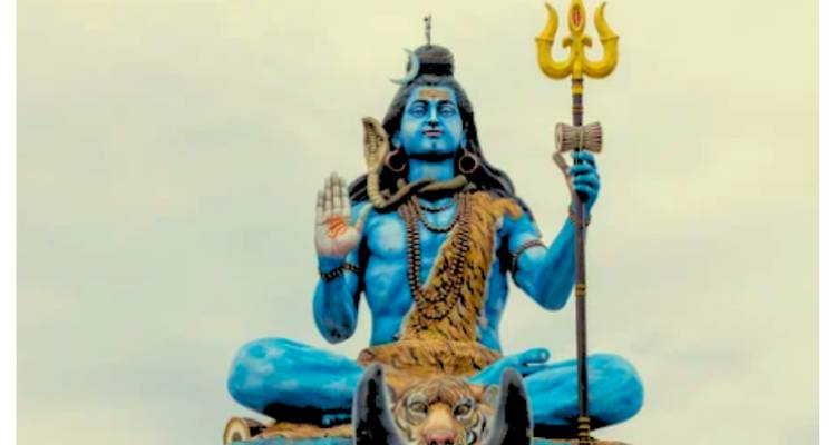 A large colorful statue of a deity sitting in a meditative pose with a tiger skin and holding a trident.