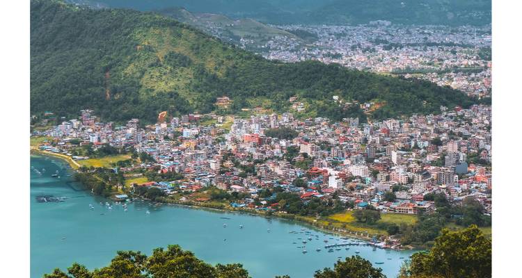 Aerial view of a city beside a large lake surrounded by hills with numerous buildings.