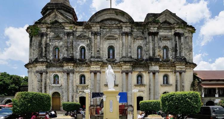 Historic stone church with a large statue in the foreground.