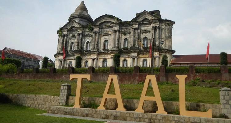 Stone church behind large letters spelling 'TAAL' in a grassy area.