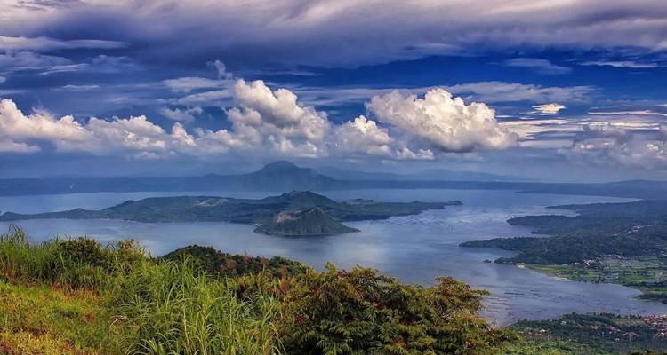 Panoramic view of a lake and volcanic island with dramatic clouds.