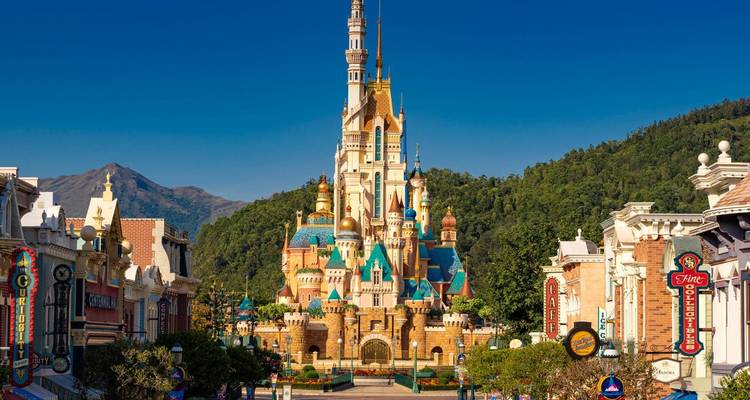 Main street view of a theme park with a tall castle.