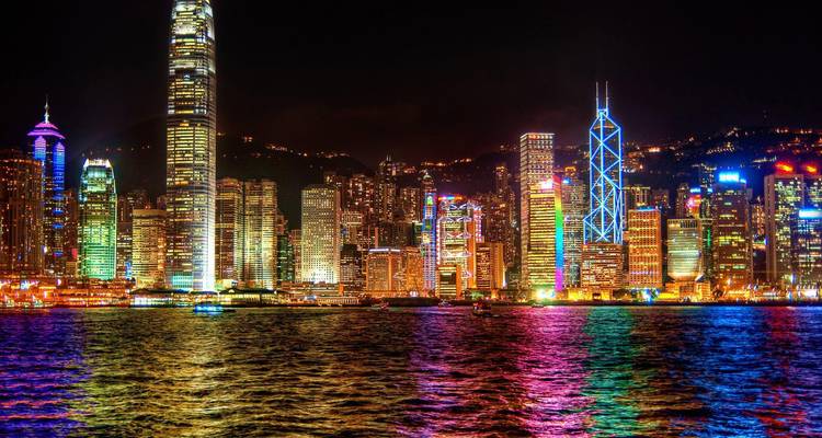 Brightly lit cityscape at night with skyscrapers along the water.