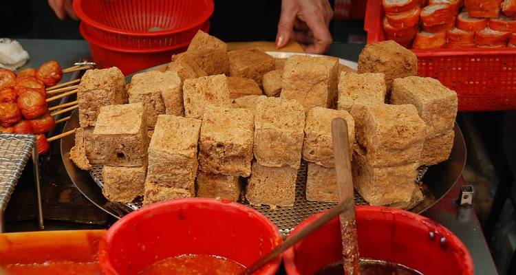 A variety of street food items with sauces in a market setting.