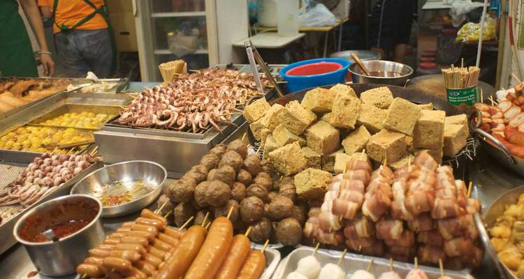 Assorted street food items laid out at a market stall.