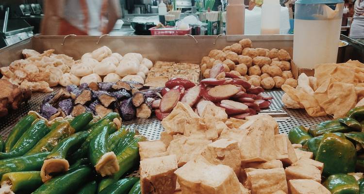 Various street food items displayed at a market with people in the background.