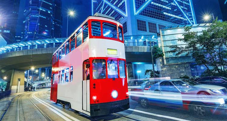 Colorful tram in a city with bright lights at night.