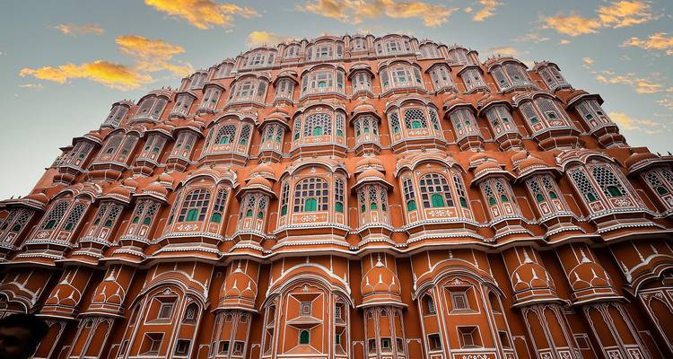 La façade complexe du Hawa Mahal sur un fond de ciel orange.