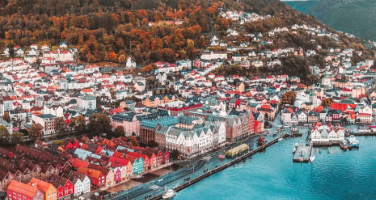 Aerial view of a colorful coastal town with rows of red, white, and yellow buildings near the water.
